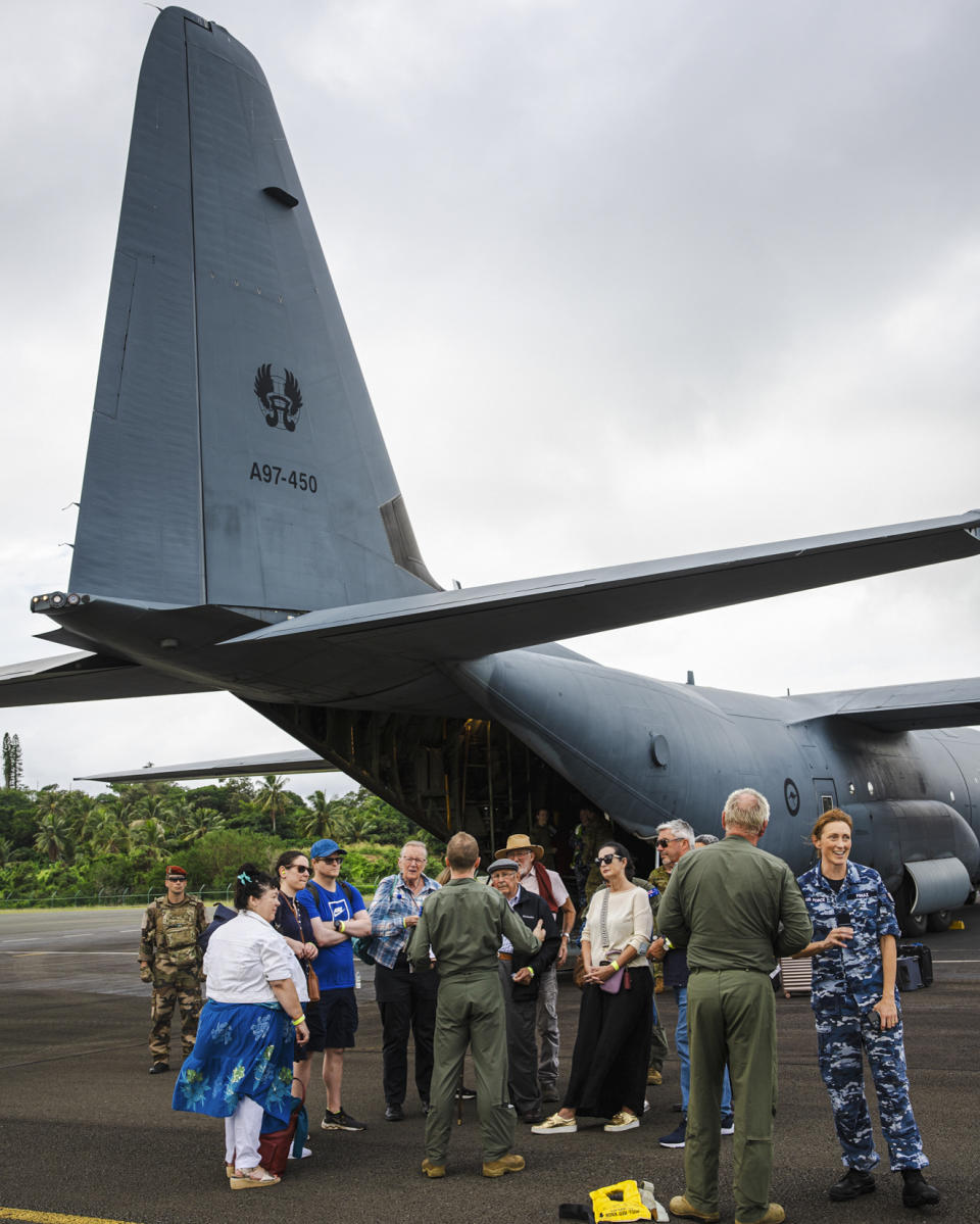 In this photo provided by the Australian Department of Defence, officials from the Department of Foreign Affairs and Trade (DFAT) assist Australian and other tourists as they prepare to depart from Magenta Airport in Noumea, New Caledonia, Tuesday, May 21, 2024. Australia and New Zealand have sent airplanes to New Caledonia to begin bringing home stranded citizens from the violence-wracked French South Pacific territory. (LAC Adam Abela/Royal Australian Airfare via AP)