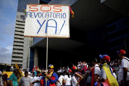 An opposition supporter holds a placard that reads "S.O.S. Recall now!" during a rally to demand a referendum to remove Venezuela's President Nicolas Maduro in Caracas, Venezuela September 1, 2016. REUTERS/Marco Bello
