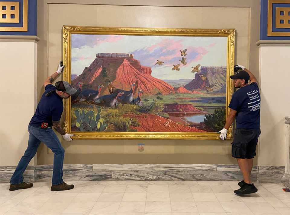 Professional art handlers contracted by the Oklahoma Arts Council install Oklahoma artist Harold T. Holden's oil painting “Game Birds at Glass Mountain” at the state Capitol.