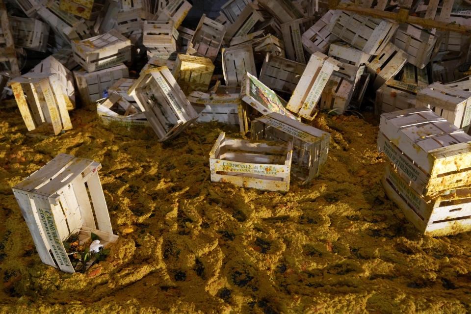 Smashed oranges are scattered on the ground among boxes following the 'Battle of the Oranges" where people pelt each other with oranges as part of Carnival celebrations in the northern Italian Piedmont town of Ivrea, Italy, Tuesday, Feb. 13, 2024. (AP Photo/Antonio Calanni)