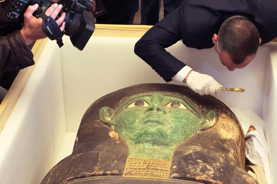 Mostafa Waziri, top official at the Supreme Council of Antiquities, takes a look with a magnifier at an ancient wooden sarcophagus during a handover ceremony at the foreign ministry in Cairo, Egypt, Monday, Jan. 2, 2023.