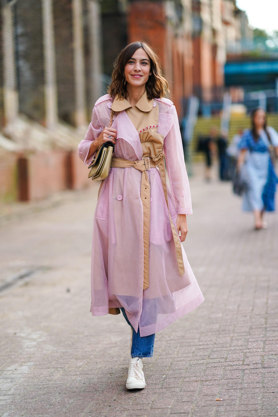 Alexa Chung is seen wearing a pale pink mesh trench coat and jeans. [Photo: Getty Images]