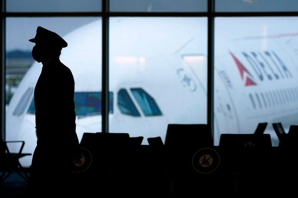 <p>Charlie Riedel/AP</p> Delta pilot walking through airport terminal 