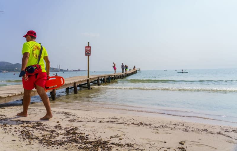 A "lifeguard" walks on the beach of Alcudia. German vacationer drowned during boat trip on Mallorca. Andreas Arnold/dpa