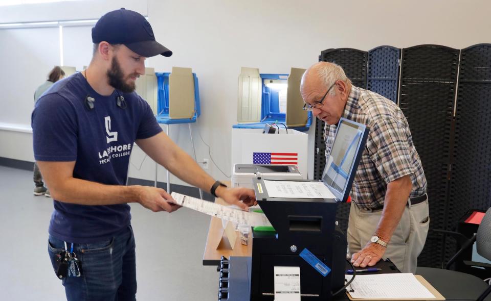 Voter Kreg Freese places his ballot in the tabulator as a poll worker observes at the Humane Society poll during the election primary, Tuesday, August 9, 2022, in Sheboygan, Wis.