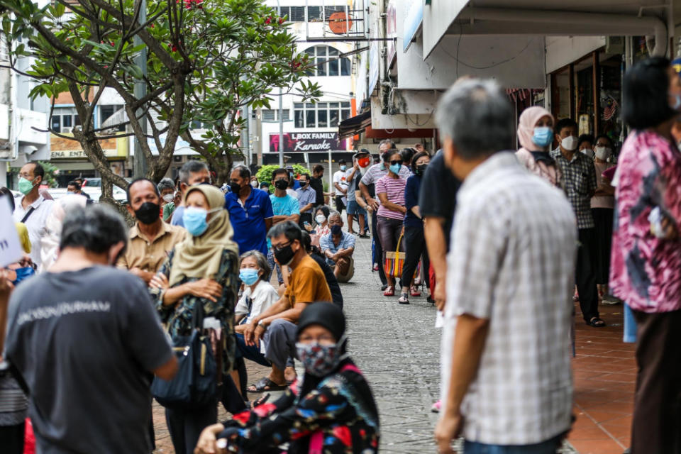 People queue to get their Covid-19 booster shot at a vaccination centre in Vision College, Kelana Jaya January 4, 2022. — Picture by Hari Anggara