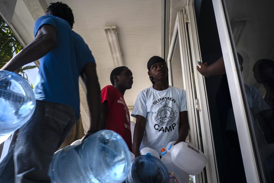 People line up to buy water at a store before the arrival of Hurricane Dorian, in Freeport, Bahamas, Friday, Aug. 30, 2019. Forecasters said the hurricane is expected to keep on strengthening and become a Category 3 later in the day. (AP Photo/Ramon Espinosa)