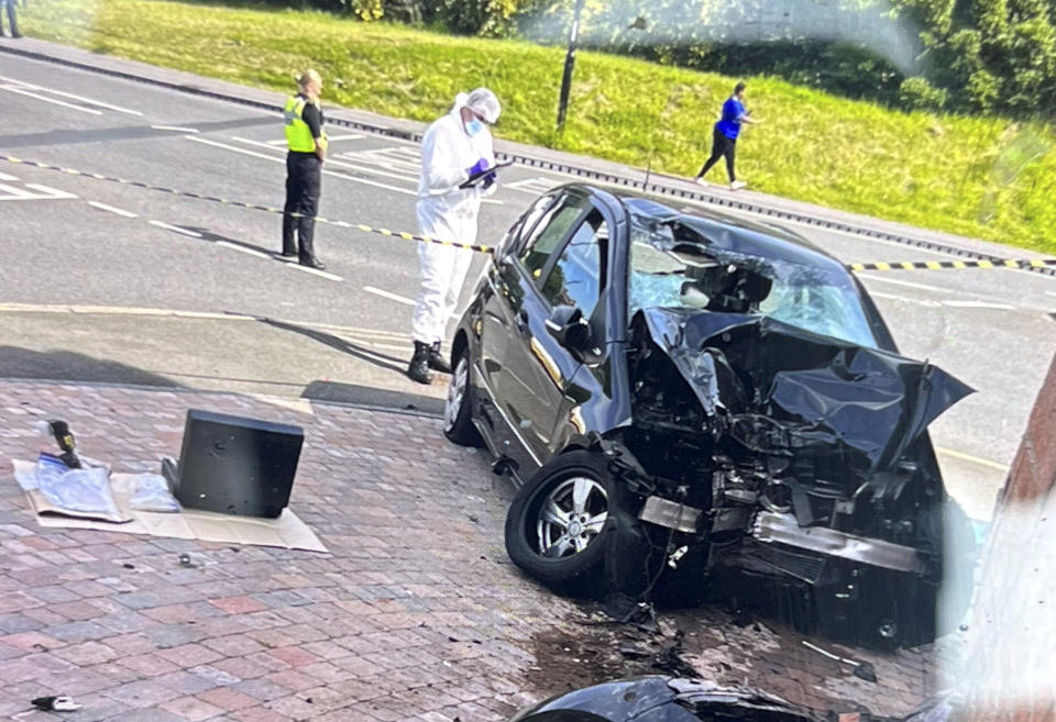 A forensics worker examines a car after it crashed into a property in Coventry. (SWNS)