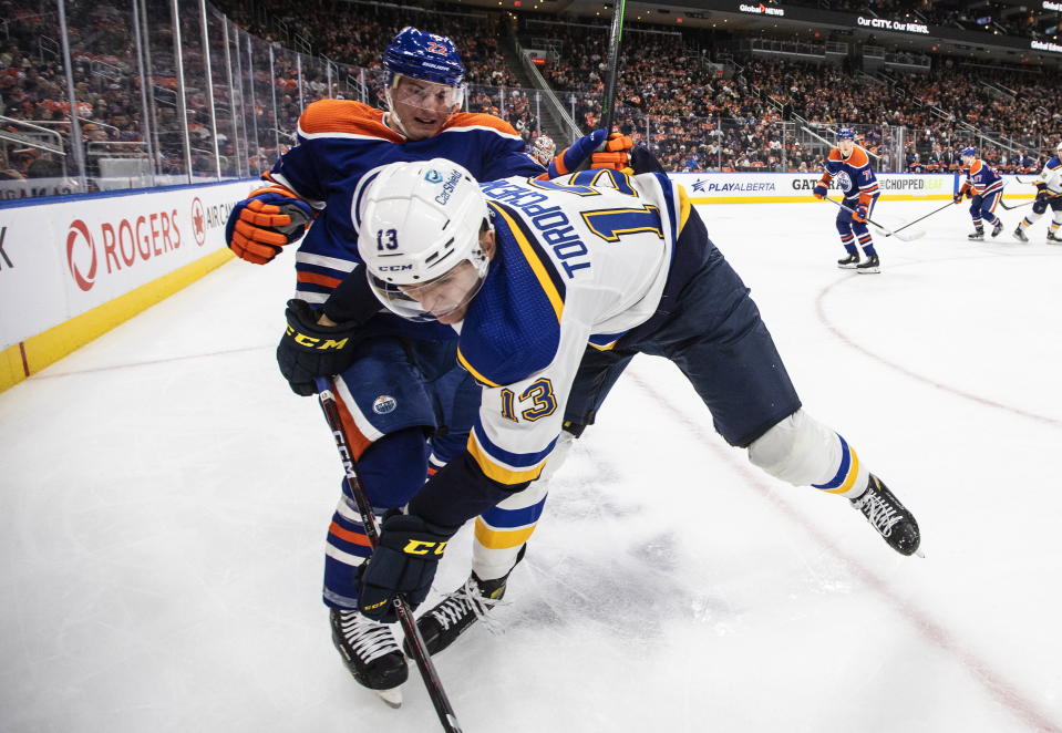 St. Louis Blues' Alexei Toropchenko (13) is checked by Edmonton Oilers' Tyson Barrie (22) during the third period of an NHL game in Edmonton, Alberta, Saturday, Oct. 22, 2022. (Jason Franson/The Canadian Press via AP)