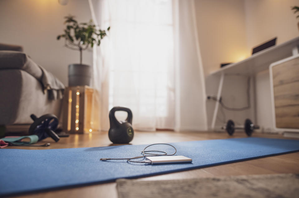 Power bank on yoga mat in living room with kettlebell and exercise equipment
