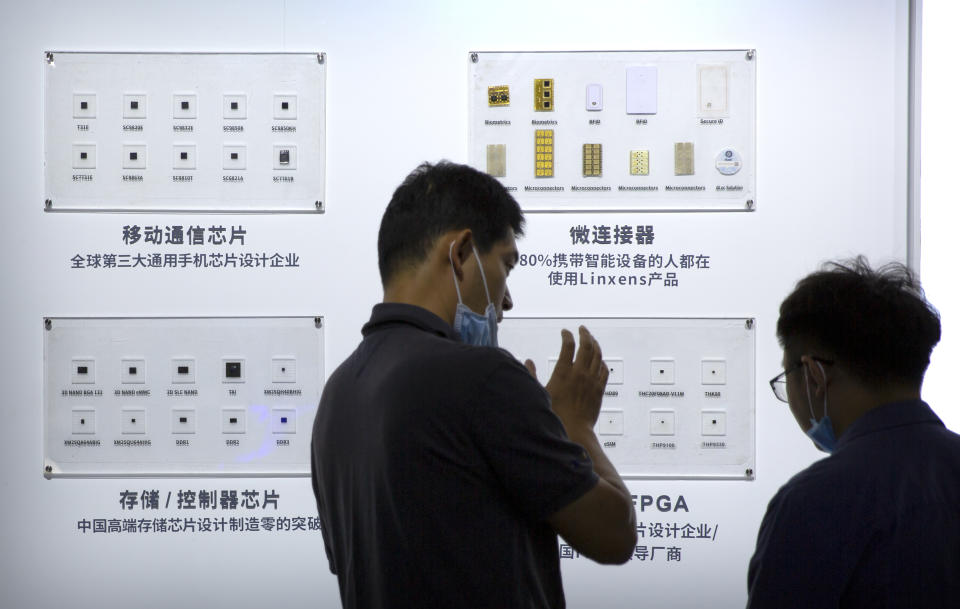 People look at semiconductors on display from the Tsinghua Unigroup at the China Beijing International High Tech Expo in Beijing, Saturday, Sept. 19, 2020. Chinese leaders are shifting focus from the coronavirus back to long-term goals of making China a technology leader at this year's highest-profile political event, the meeting of its ceremonial legislature, amid tension with Washington and Europe over trade, Hong Kong and human rights. (AP Photo/Mark Schiefelbein)