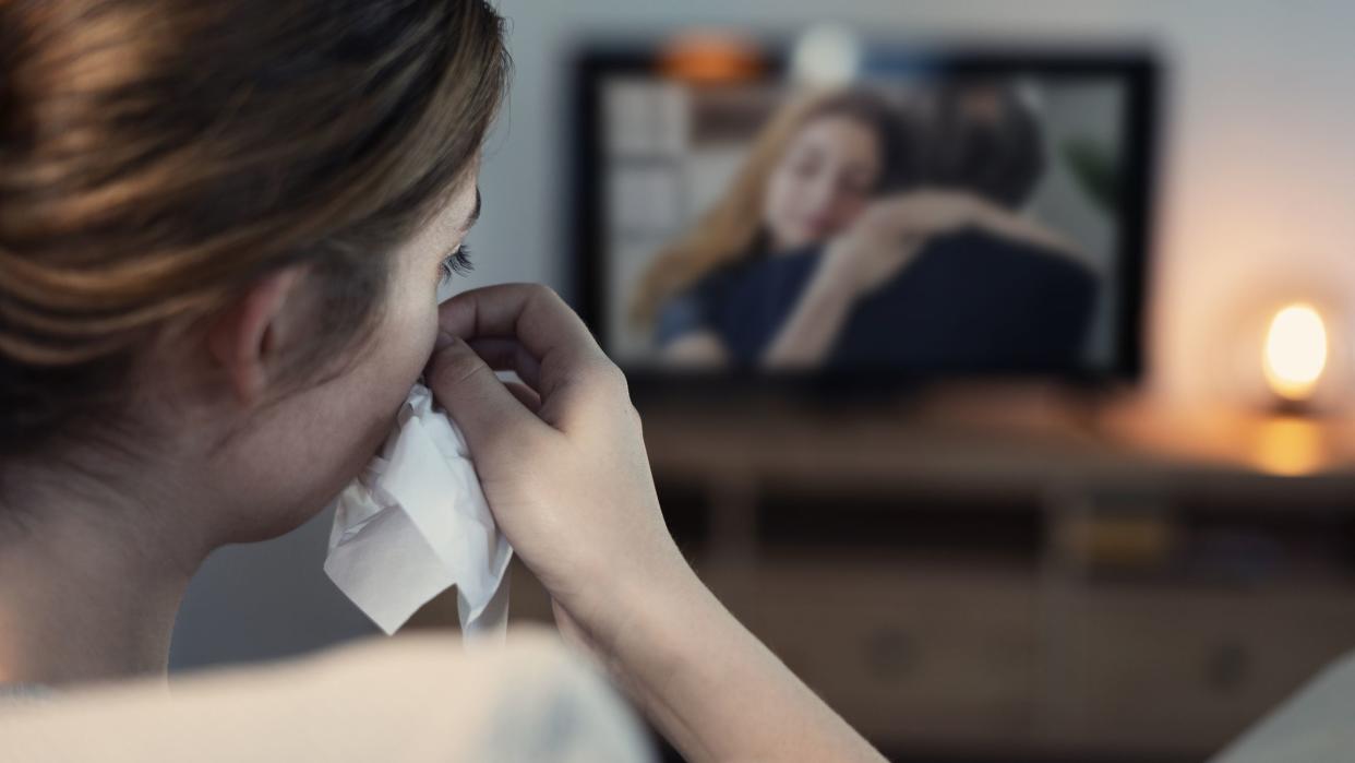 Woman crying while watching tv in the night