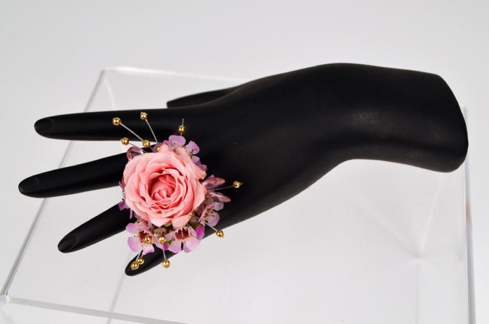 This product image released by Gillespie Florists, Inc. shows a flower ring. The decoration is created with a pink sweetheart rose, wax flower, beads and a few rhinestones. (AP Photo/Gillespie Florists, Inc.)