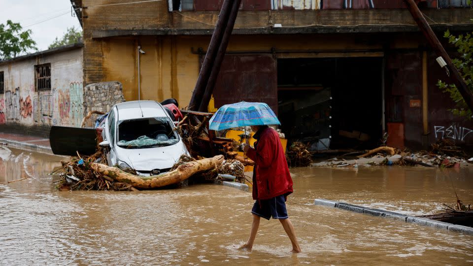 A man holding an umbrella walks on a flooded road in Volos, Greece. - Louisa Gouliamaki/Reuters