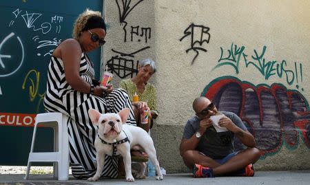 People eat street market-purchased food and drinks including pasteis de feira (pastries) in Rio de Janeiro, Brazil, May 7, 2016. REUTERS/Sergio Moraes