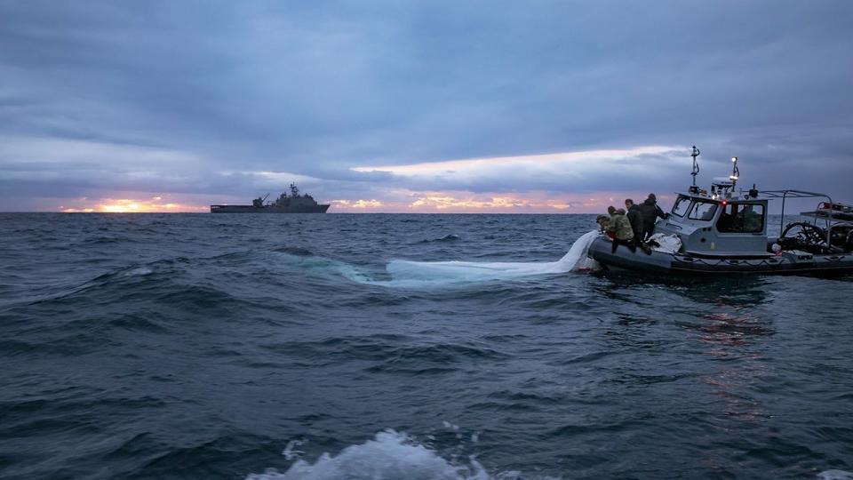 Sailors assigned to Explosive Ordnance Disposal Group 2 recover a high-altitude surveillance balloon off the coast of Myrtle Beach, South Carolina, while the Harpers Ferry-class dock landing ship USS Carter Hall (LSD 50) transits nearby, Feb. 5, 2023. EODGRU 2 is a critical part of the Navy Expeditionary Combat Force that clears explosive hazards to provide access to denied areas; secures the undersea domain for freedom of movement; builds and fosters relationships with trusted partners, and protects the homeland. At the direction of the President of the United States and with the full support of the Government of Canada, U.S. fighter aircraft under U.S. Northern Command authority engaged and brought down a high altitude surveillance balloon within sovereign U.S. airspace and over U.S. territorial waters Feb. 4, 2023.  Active duty, Reserve, National Guard, and civilian personnel planned and executed the operation, and partners from the U.S. Coast Guard, Federal Aviation Administration, and Federal Bureau of Investigation ensured public safety throughout the operation and recovery efforts.