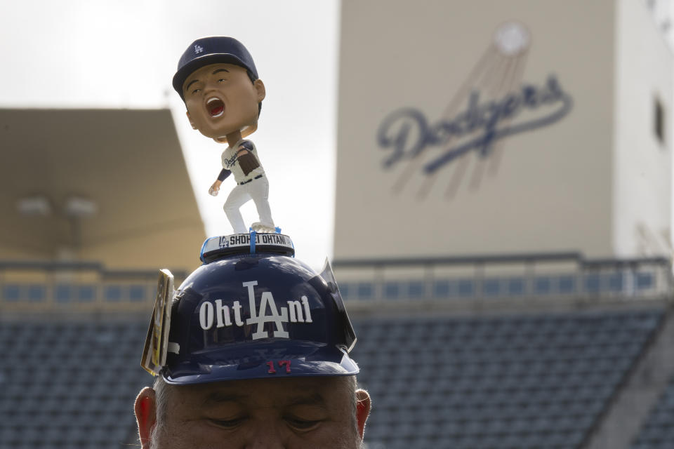 Los Angeles Dodgers fan Alberto Valenzuela attends the team's fan fest wearing a helmet with a Shohei Ohtani bobblehead on top in Los Angeles, Saturday, Feb. 3, 2024. (AP Photo/Kyusung Gong)