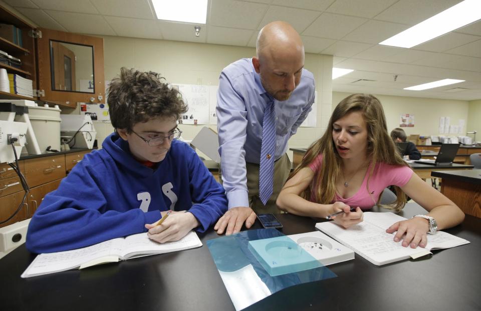 Matthew Davis, left, and Shannon Newerth study the habits of bugs with teacher Chris Kaufman during a Plant and Soil Science class at Beech Grove High School Wednesday, April 30, 2014, in Indianapolis. High school agriculture programs sprouting across the nation’s Corn Belt are teaching teenagers, many of them in urban environments, that careers in the field often have nothing to do with cows and plows. (AP Photo/Darron Cummings)