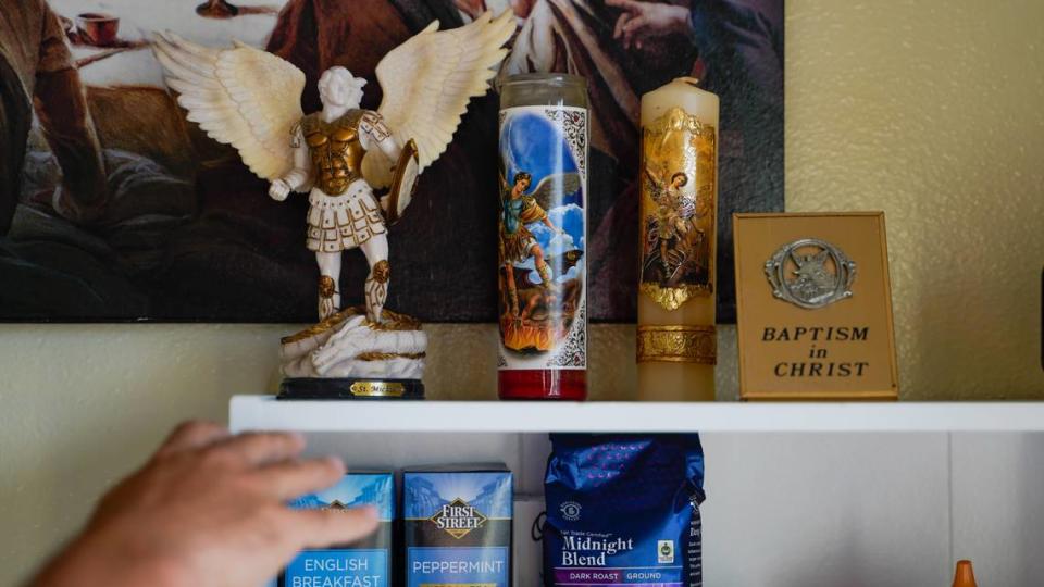 Luke, an Arroyo Grande resident who recently moved into a permanent home using a housing choice voucher, reaches for a statue of Saint Michael.