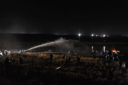 Police use a water cannon to put out a fire started by protesters during a protest against plans to pass the Dakota Access pipeline near the Standing Rock Indian Reservation, near Cannon Ball, North Dakota, U.S. November 20, 2016. REUTERS/Stephanie Keith
