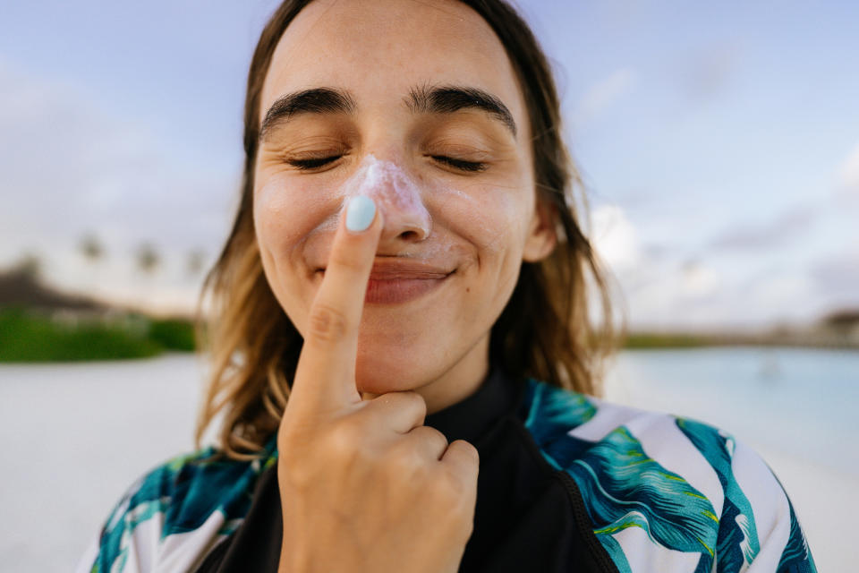 Women with sunscreen on her nose at the beach wearing a tropical wetsuit