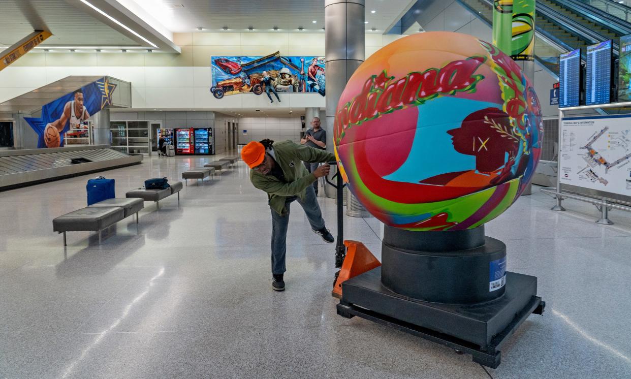 Tony Bryant, with Hand N Hand Transportation, places Koda Witsken’s artist-produced basketball, titled “Indiana’s Title IX Legacy,” in position Thursday, Feb. 8, 2024 at the Indianapolis International Airport, in the baggage claim area. The public art pieces will be around Indianapolis for the NBA All-Star Indy 2024 weekend.