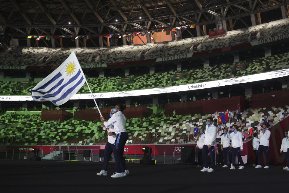 Deborah Rodríguez y Bruno Cetraro Berriolo, de Uruguay, portan la bandera de su país durante la ceremonia de inauguración de los Juegos Olímpicos de Tokio 2020 en el estadio olímpico el 23 de julio de 2021 en Tokio, Japón. (Hannah McKay/Pool Photo via AP)