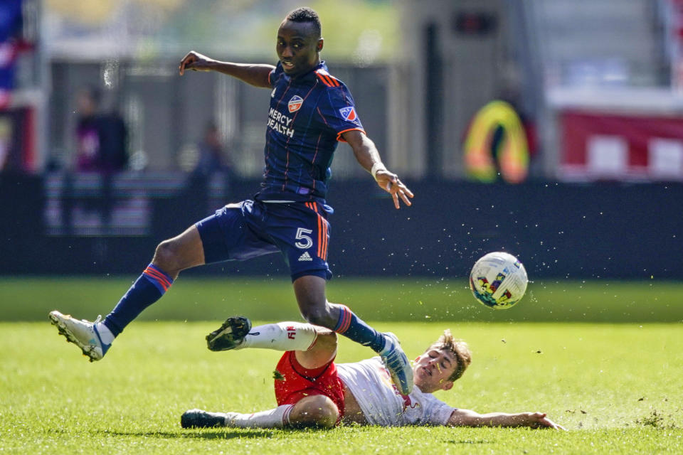 New York Red Bulls midfielder Daniel Edelman slides in to tackle the ball away from FC Cincinnati midfielder Obinna Nwobodo (5) during the second half of an MLS soccer playoff match, Saturday, Oct. 15, 2022, in Harrison, N.J. (AP Photo/Eduardo Munoz Alvarez)