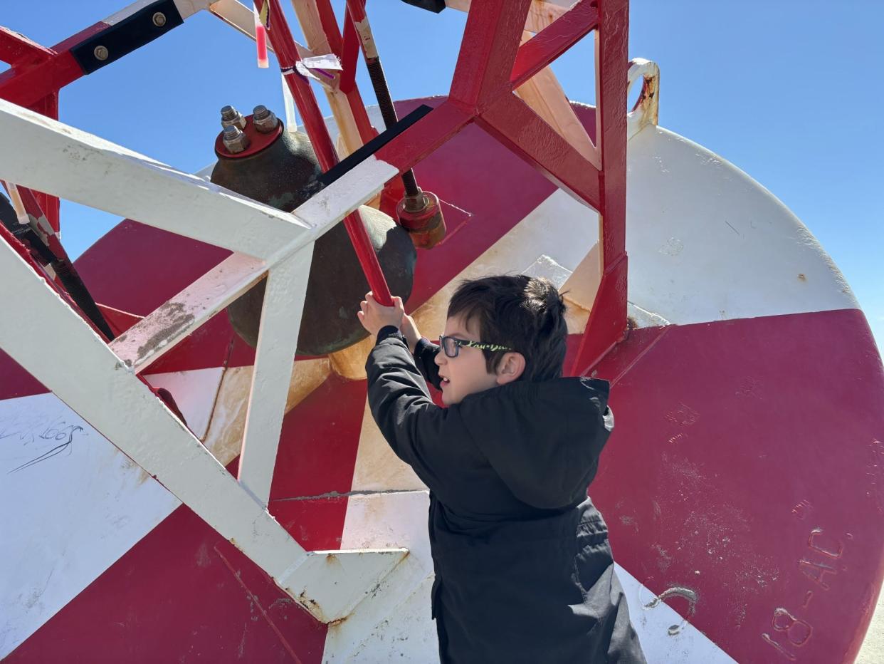 Arlo St. Onge, of Wells, rings the bell of the buoy that washed up on shore at Wells Beach in Maine, following a storm in early April 2024.