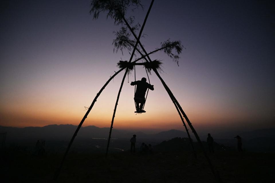 A boy sways on a swing traditionally called the 'Dashain Ping' on the occasion of the  Nepali Hindu festival 'Dashain' (AFP via Getty Images)