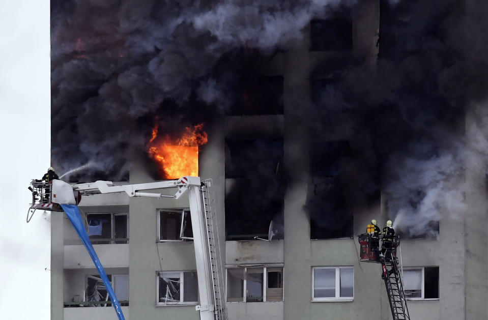 Firefighters on a ladder try to extinguish a fire in a 12-storey apartment block after a gas explosion in Presov, Slovakia, Friday, Dec. 6, 2019. Officials say a gas explosion in an apartment block in Slovakia has killed at least five people and others are trapped on the roof of the building. Firefighters say the explosion occurred in a 12-story building in the city of Presov shortly after noon on Friday. (Frantisek Ivan/TASR via AP)