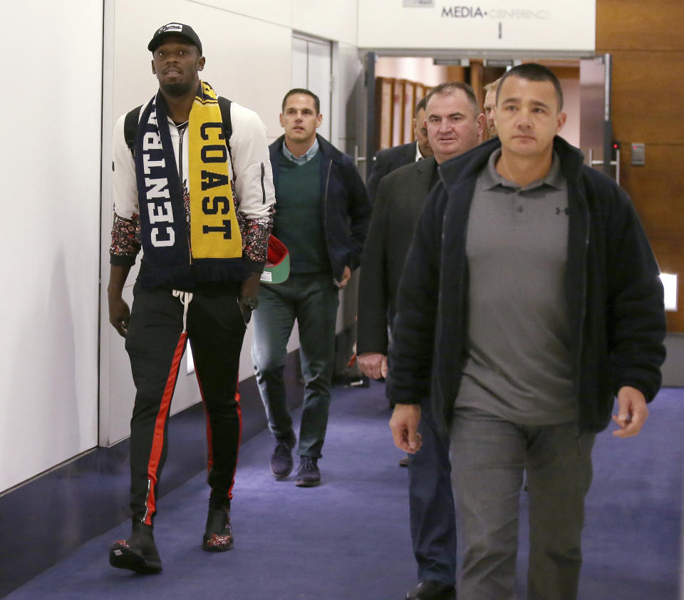 Jamaica's Usain Bolt, left, arrives in Sydney, Saturday, Aug. 18, 2018. Olympic gold medalist, Bolt is hoping to impress the coaching staff enough to earn a contract with the Central Coast Mariners for the 2018-19 season in Australia's top-flight soccer competition. (AP Photo/Rick Rycroft)