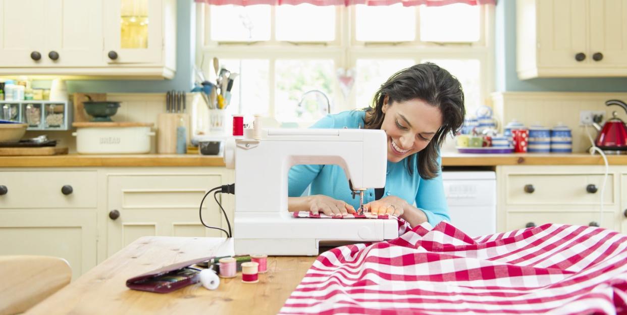 hispanic woman using sewing machine on kitchen table