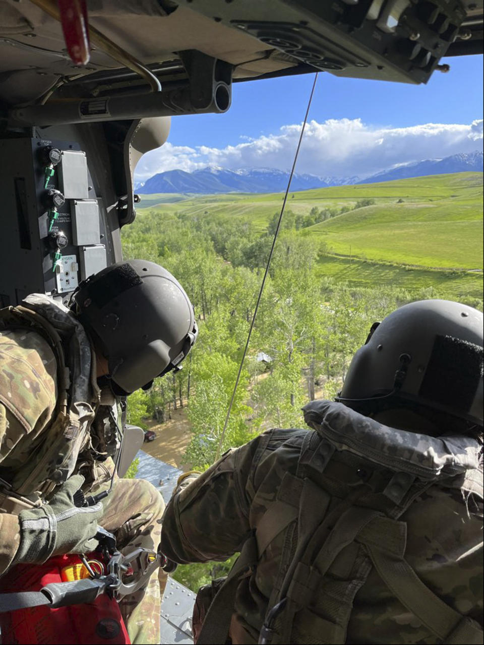 RETRANSMISSION TO CORRECT DAY AND DATE TO TUESDAY, JUNE 14 - In this photo released by the Montana National Guard, helicopter crew members are seen supporting search and rescue operations near Yellowstone National Park, Tuesday, June 14, 2022. Floodwaters that rushed through Yellowstone National Park and surrounding communities earlier this week are moving through Montana's largest city, flooding farms and ranches and forcing the shutdown of its water treatment plant. (Montana National Guard via AP)