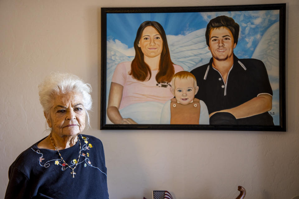 Donna Casasanta poses in front of a painting showing her late son, Harold Dean Clouse, with Clouse's wife, Tina Gail Linn, and their daughter, Hollie Marie Clouse, at Casasanta's Edgewater, Fla., home on Friday, Jan. 14, 2022. Clouse and Linn were murdered 40 years ago and recently identified using genealogical evidence, though the family hopes Hollie is still alive. (Patrick Connolly/Houston Chronicle via AP)