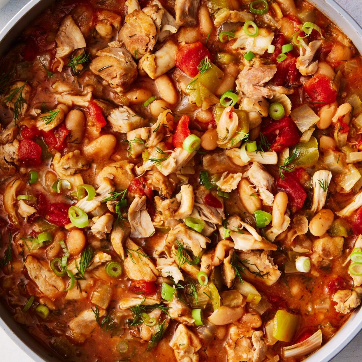 chili in a bowl with chicken, tomatoes, and green onions