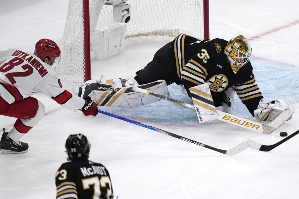 Boston Bruins goaltender Linus Ullmark (35) covers the puck while pressured by Carolina Hurricanes center Jesperi Kotkaniemi (82) during the second period of an NHL hockey game Wednesday, Jan. 24, 2024, in Toronto. (Nathan Denvette/The Canadian Press via AP)