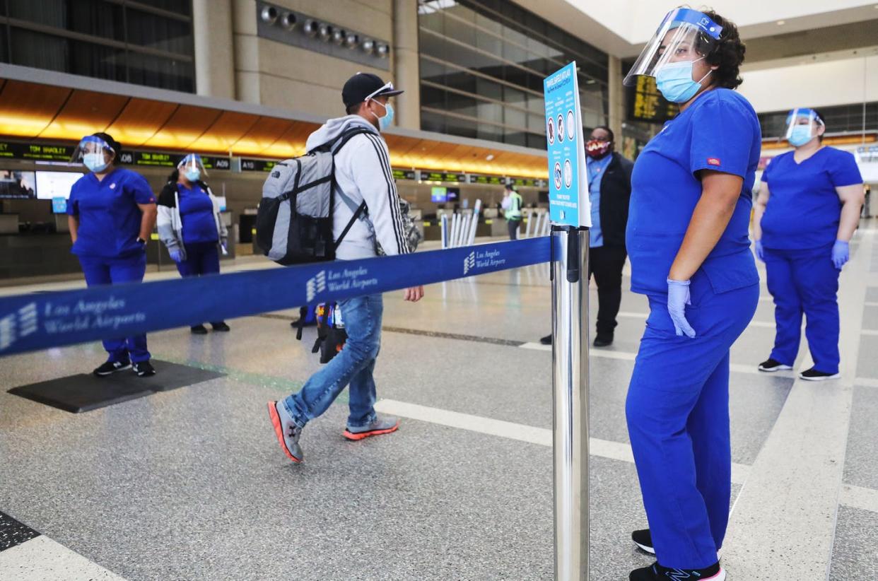 <span class="caption">A traveler walks past screeners testing a system of thermal imaging cameras which check body temperatures at Los Angeles International Airport on June. 24, 2020.</span> <span class="attribution"><a class="link " href="https://www.gettyimages.com/detail/news-photo/traveler-walks-past-screeners-testing-a-system-of-thermal-news-photo/1252247135?adppopup=true" rel="nofollow noopener" target="_blank" data-ylk="slk:Mario Tama/Getty Images;elm:context_link;itc:0;sec:content-canvas">Mario Tama/Getty Images</a></span>