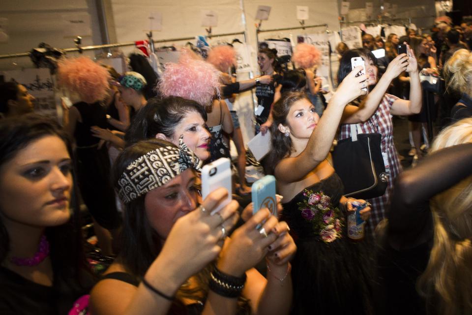 Onlookers take photographs of models backstage before the Betsey Johnson Spring 2014 collection is modeled during Fashion Week in New York, Wednesday, Sept. 11, 2013. (AP Photo/John Minchillo)
