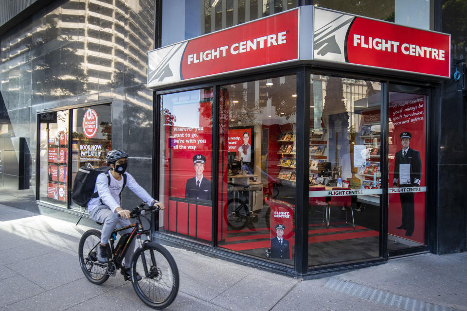 A cyclist rides past a Flight Centre store wearing a mask to protect themselves from Covid-19, Brisbane, Friday, May 1, 2020. (AAP Image/Glenn Hunt) NO ARCHIVING