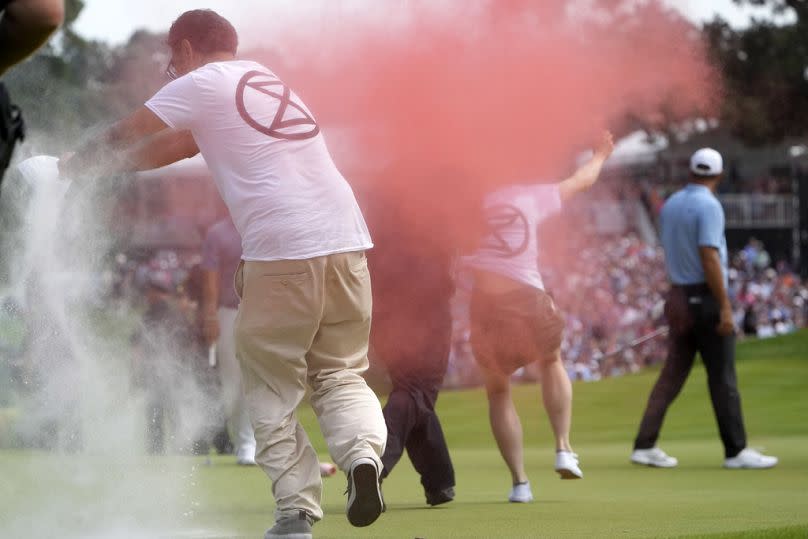 Extinction Rebellion protestors run onto the 18th green at the PGA Travelers Championship in Connecticut, USA.