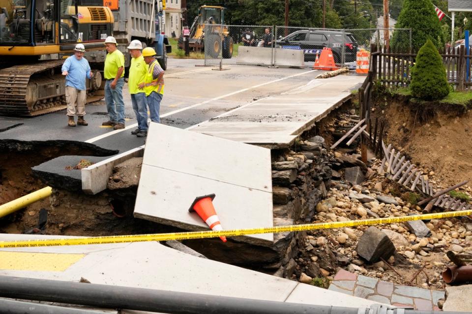 Public works officials examine the damage to a road and front yard that was washed away by recent flooding, Wednesday, Sept. 13, 2023, in Leominster, Mass. (AP)