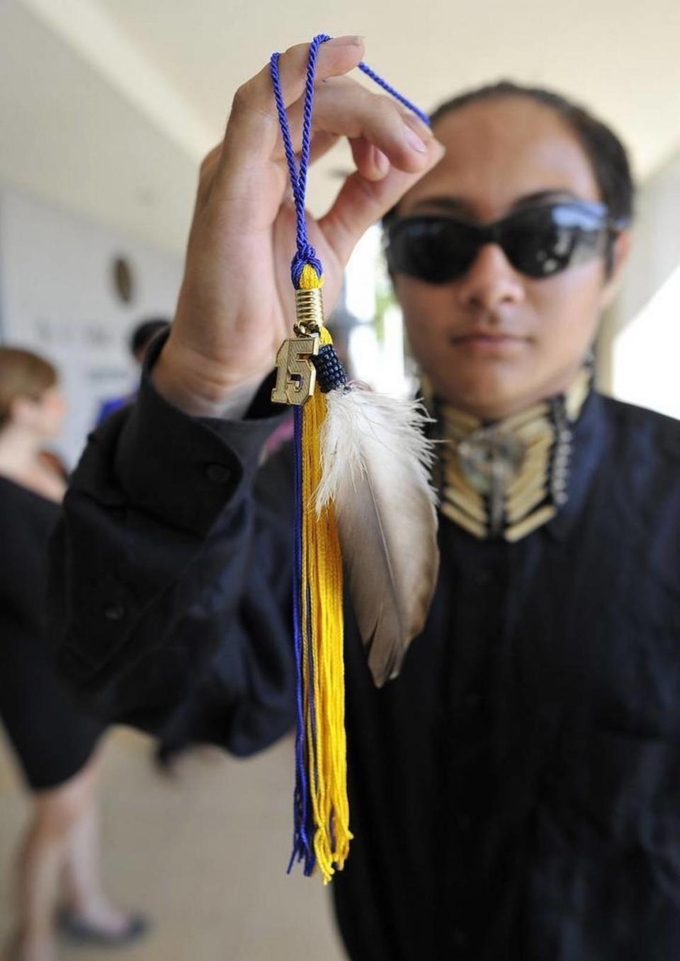 El estudiante de último año de Clovis High Christian Titman sostiene su borla de graduación con una pluma de halcón, después de una audiencia en el B.F. Sisk Courthouse. Quiere llevar una pluma de águila durante las ceremonias de graduación.