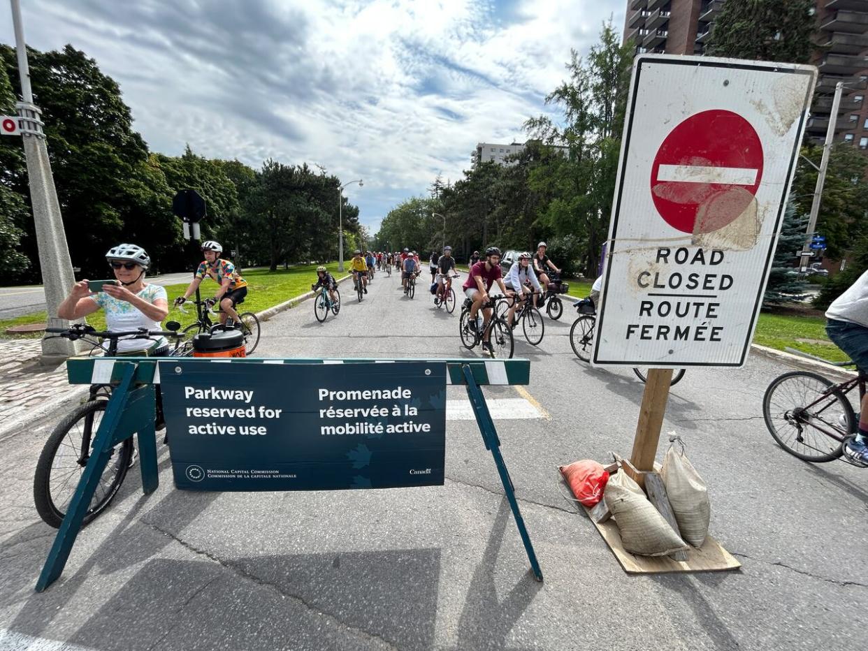 About 200 cyclists took part in a 'critical mass' bike ride Saturday that took them up the Queen Elizabeth Driveway, the parkway where vehicles are limited during the summer.  (Guy Quenneville/CBC - image credit)