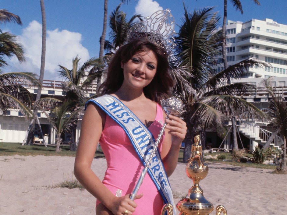 Miami Beach, Fla.: Miss Lebanon, Georgina Rizk is shown with crown, cup and sceptre on beach here the morning after she became Miss Universe.