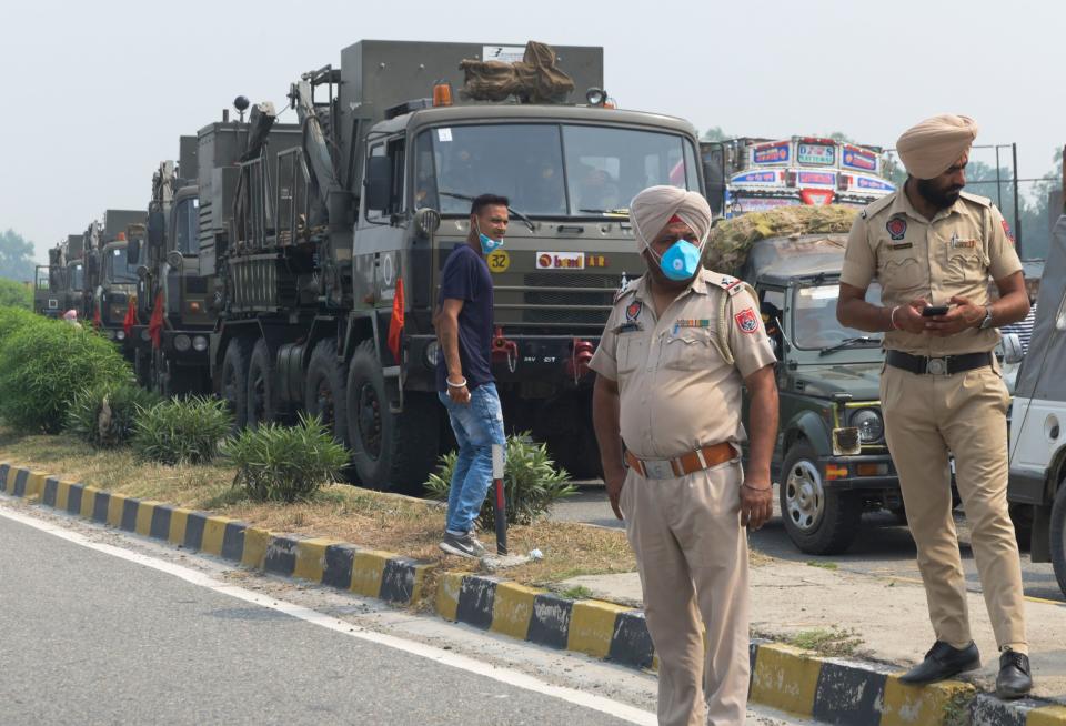 Punjab Police personnel stand guard near the Army convoy along a national highway blocked by farmers during a nationwide farmers' strike following the recent passing of agriculture bills in the Lok Sabha (lower house), on the outskirts of Amritsar on September 25, 2020. (Photo by NARINDER NANU/AFP via Getty Images)