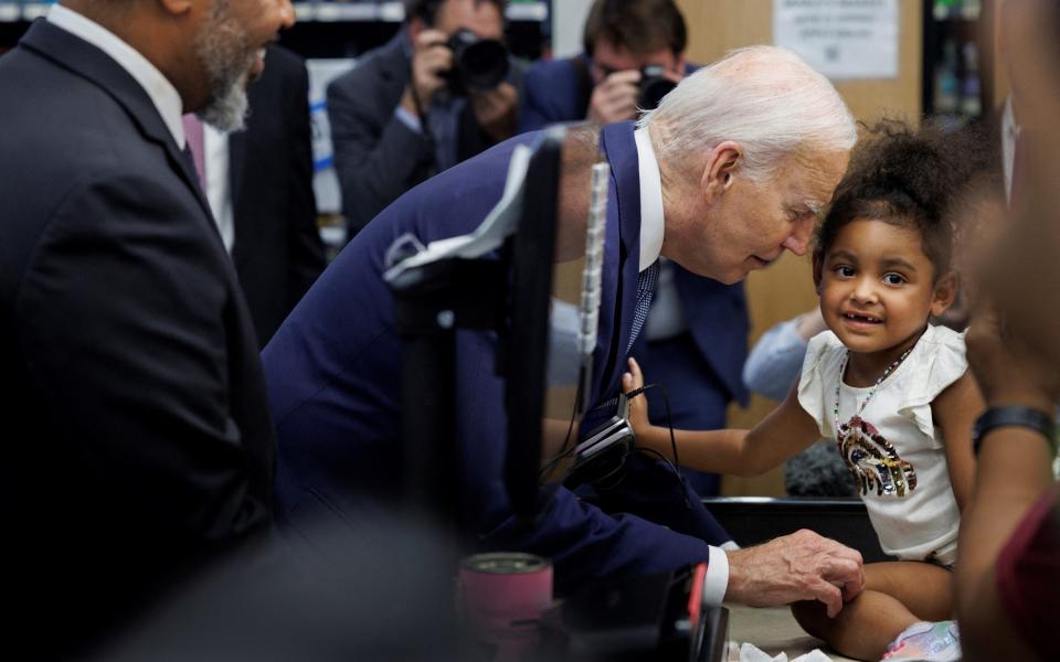 Joe Biden greets a young girl during a campaign visit to Mario's Westside Market grocery store in Las Vegas