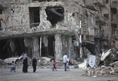 People walk along a damaged street filled with debris in Deir al-Zor September 4, 2013. REUTERS/Khalil Ashawi