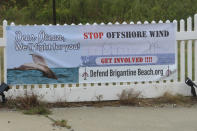 An anti-offshore wind sign is draped across a fence in the driveway of a homeowner in Brigantine, N.J., on Wednesday, Sept. 18, 2024. (AP Photo/Wayne Parry)