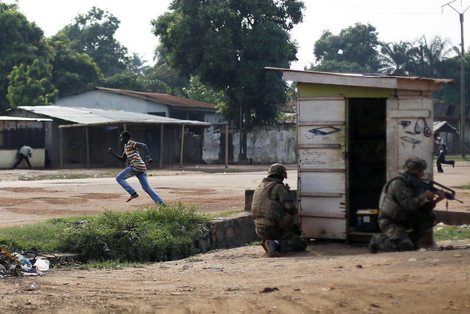 Men run across the Avenue de France while French forces take cover as heavy gunfire erupts in the Miskin district of Bangui, Central African Republic, Monday Feb. 3, 2014. In what a French soldier on the scene describes as the heaviest exchange of fire he'd seen since early December 2013, Muslim militias engaged Burundi troops who returned fire. A third source of firing remained unidentified. Fighting between Muslim Seleka militias and Christian anti-Balaka factions continues as French and African Union forces struggle to contain the bloodshed. (AP Photo/Jerome Delay)